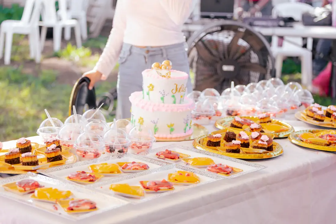 A party dessert table with small cakes and sweets on white linen